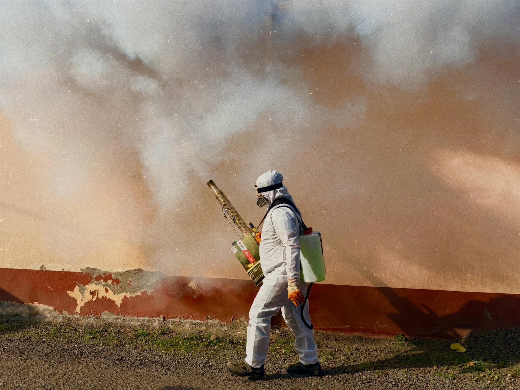 Professional pest control technician treating a home exterior with specialized equipment